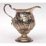George V cream jug of circular baluster form in George II style, heavily chased and embossed with