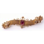 Victorian 9ct gold, ruby and seed pearl bar brooch, the centre oval faceted ruby framed on a