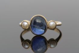 Sapphire and pearl ring, centring an oval cabochon sapphire between two small seed pearls, each