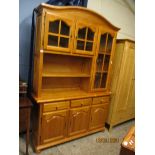 STAINED PINE DISPLAY CABINET, THE TOP FITTED WITH THREE GLAZED DOORS WITH OPEN SHELF, THE BASE