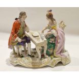 Continental porcelain group of a lady and gentleman, the lady playing the piano, on a scroll gilt