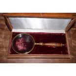 Magnifying glass 10cm dia with brass surround, in wooden case 27 x 13 x 5cm.