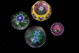 Group of four paperweights including a Baccarat primrose weight with a blue flower with white