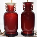Pair of Chinese Sang de-boeuf lamps, the vases seated on wooden bases with brass mounts for