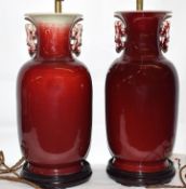 Pair of Chinese Sang de-boeuf lamps, the vases seated on wooden bases with brass mounts for