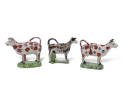 Group of three early 19th century Staffordshire cow creamers, two with sponged puce and red