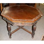 Oak dining table of octagonal form, carved top and frieze decorated with floral C-scrolls raised