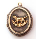 Antique silver oval locket, the front applied with a gold shield engraved with a monogram, the verso