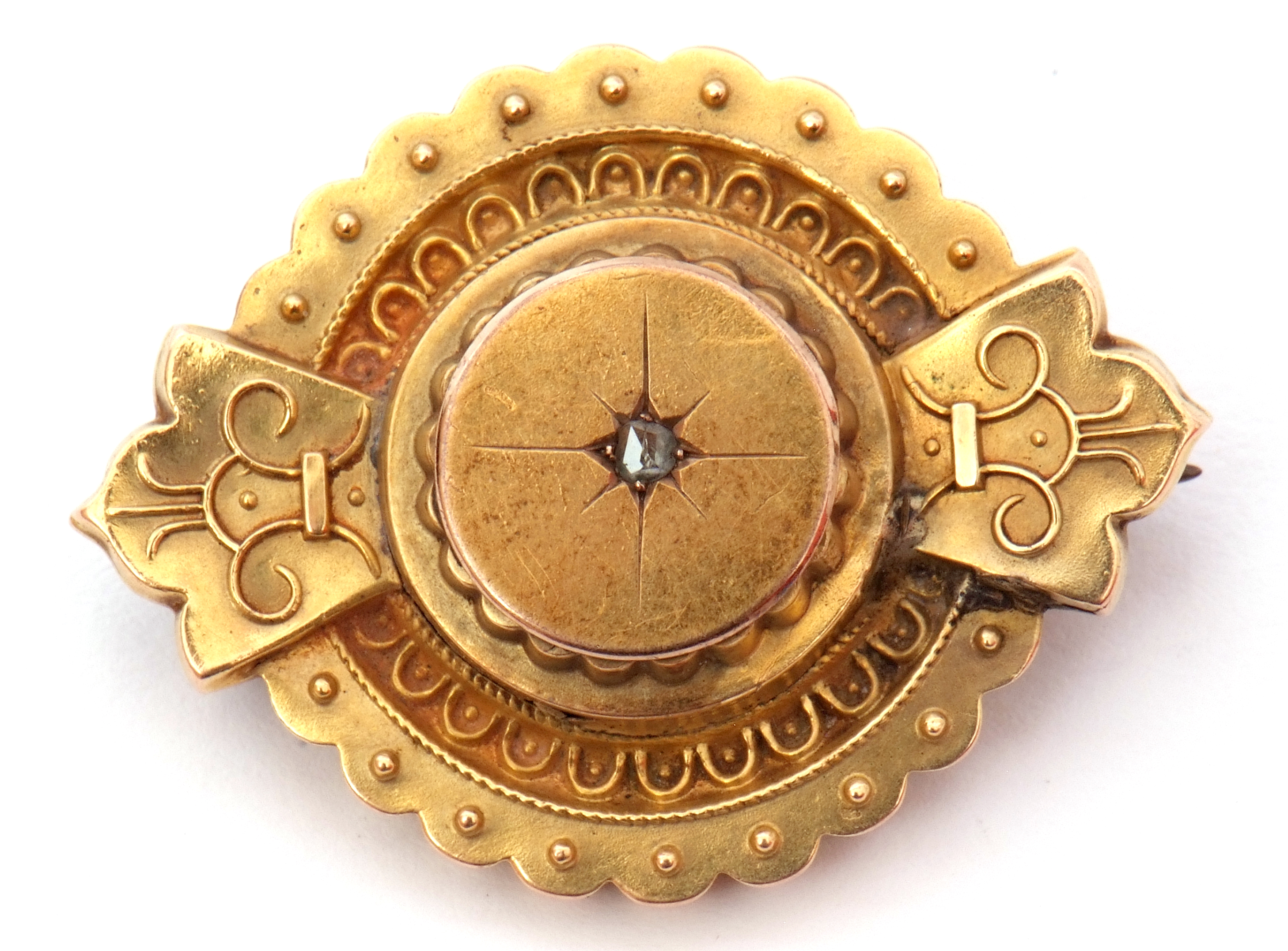 Victorian gold target brooch in Etruscan style, featuring a small central old cut diamond, glazed