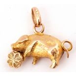 Small yellow metal pig pendant charm holding a four-leaf clover with chased and engraved detail,