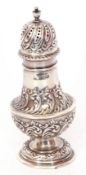 Edward VII silver caster of typical baluster form, embossed with scrolls, the pierced domed pull off