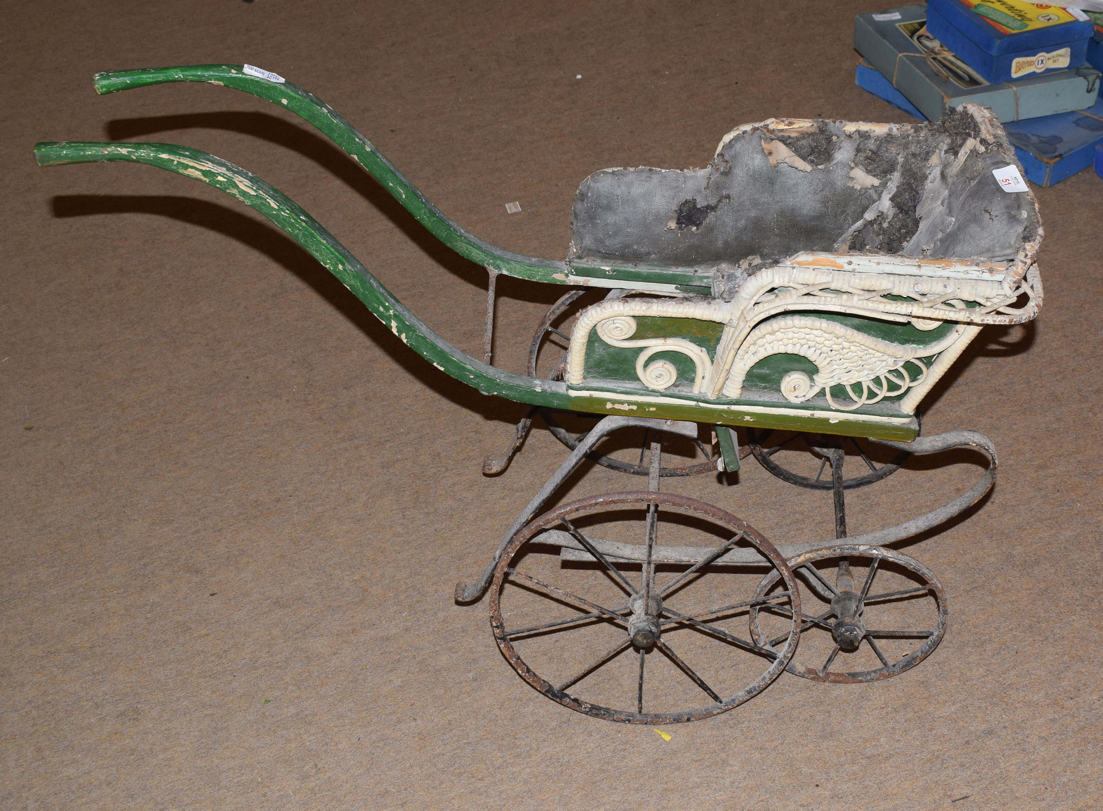 Vintage dog cart containing the remnants of original cane and fabric upholstery over a wrought