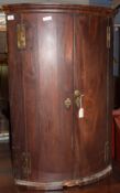 18th century mahogany bow fronted, wall hanging corner cabinet, the two doors opening to reveal