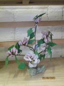 POTTERY MODEL OF A FLOWER WITH GREEN LEAVES, DECORATED IN PINK, STANDING ON AN ONYX STYLE BASE