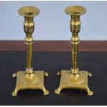 Pair of slender brass candlesticks, the spreading square bases applied with trefid feet, 23cm high