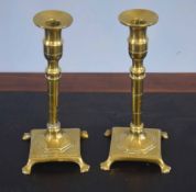 Pair of slender brass candlesticks, the spreading square bases applied with trefid feet, 23cm high