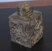 White metal caddy and cover of square section decorated with dragons in relief, the cover with