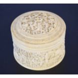 Ivory circular box and cover carved in relief with figures in a landscape, 11cm diam