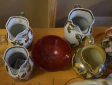 Collection of four Staffordshire jugs with gilt floral design and Prinknash Pottery bowl with red