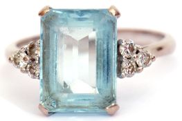 Precious metal aquamarine and diamond ring, the step cut aquamarine in a four-claw mount, flanked by