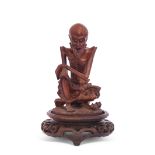 Oriental wooden carving of a sage or elderly gent seated on a wooden oval base, 13cm high