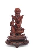 Oriental wooden carving of a sage or elderly gent seated on a wooden oval base, 13cm high