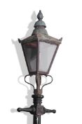 Victorian cast metal street lamp with a four glass tapering metal framed shade resting on a black