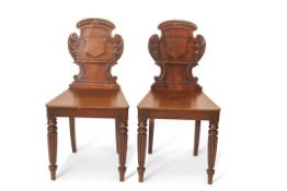 Pair of early 19th century mahogany hall chairs in the Irish manner, the short backs with