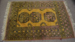 Late 20th century wool small rug, central panel of three geometric lozenges, mainly ochre and puce