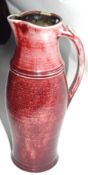 Rouge flambe style jug together with a small Art pottery jug, the largest 31cm high, indistinctly