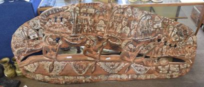 Large tribal wooden carved story board of a village scene, decorated with tribesman in canoes,