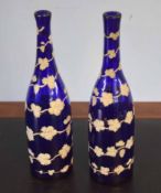 Pair of blue glass bottles overlaid with a leaf design in white and gilt, 32cm high (2)