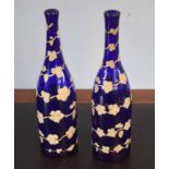 Pair of blue glass bottles overlaid with a leaf design in white and gilt, 32cm high (2)