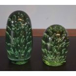 Two green glass paperweights, the largest 13cm high