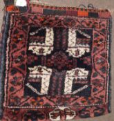 Caucasian camel bag decorated on one side with geometric designs on a mainly dark blue and puce