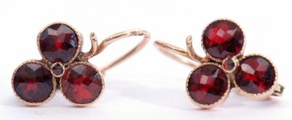 Pair of garnet earrings, each set with three circular cut garnets in collet settings with millegrain