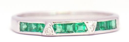 Precious metal emerald and diamond half eternity ring, alternate set with a group of 3 calibre cut