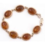 Modern 9ct gold and amber bracelet, a design featuring 7 oval cabochon amber set links, each in