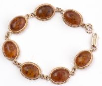 Modern 9ct gold and amber bracelet, a design featuring 7 oval cabochon amber set links, each in