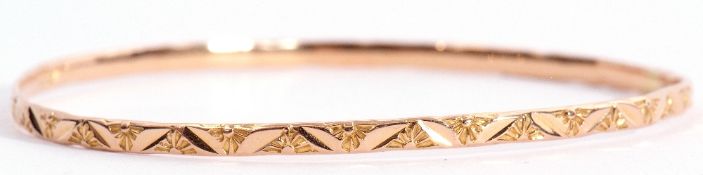 Yellow metal bangle engraved and chased with a floral design, 6.5cm diam, 8.7gms