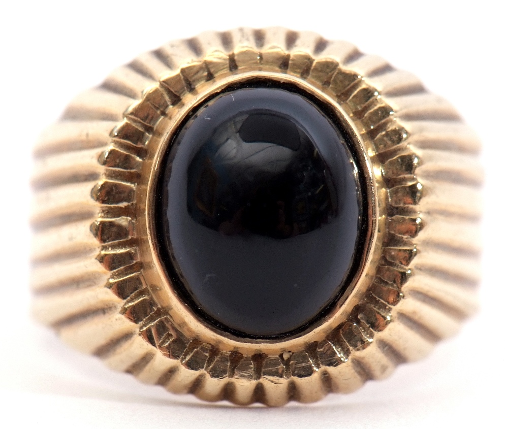 15ct stamped onyx ring, the oval shaped cabochon set in a part engraved engraved reeded mount,