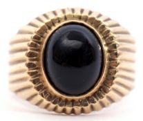 15ct stamped onyx ring, the oval shaped cabochon set in a part engraved engraved reeded mount,