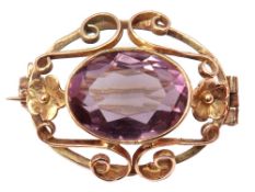 Yellow metal and amethyst brooch, the oval faceted amethyst bezel set and raised within an open work