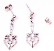 Pair of modern 9ct white gold and diamond pendant earrings, a stylised open work heart design,