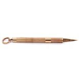 9ct gold cigar piercer, the barrel engraved and chased, with a sliding rectractable mechanism, 5cm