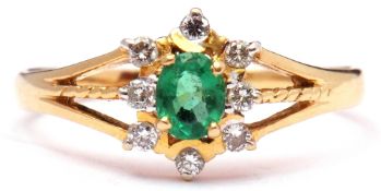 Modern emerald and diamond cluster ring centring an oval faceted emerald within an 8 diamond