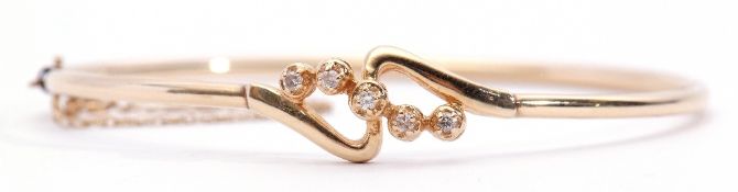 Yellow metal and diamond set hinged bracelet, a cross-over design with 5 single cut diamonds,