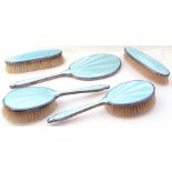 George VI five piece dressing table wares to include a hand mirror, two hair brushes and two clothes