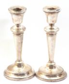 Pair of Elizabeth II silver encased candlesticks with loaded circular bases, tapering stems and