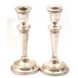 Pair of Elizabeth II silver encased candlesticks with loaded circular bases, tapering stems and